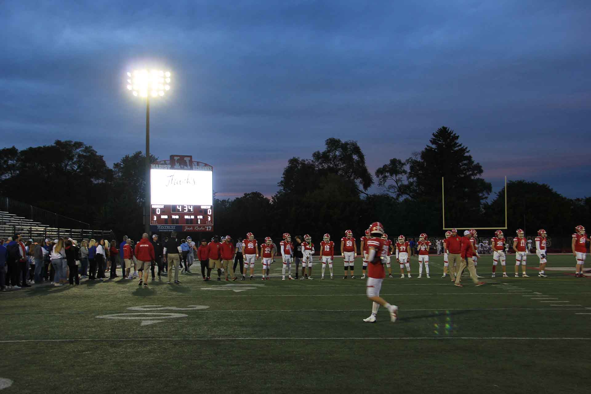 2017-5-Year-Reunion-and-Scoreboard-Dedication-football-players-and-crowd-at-night