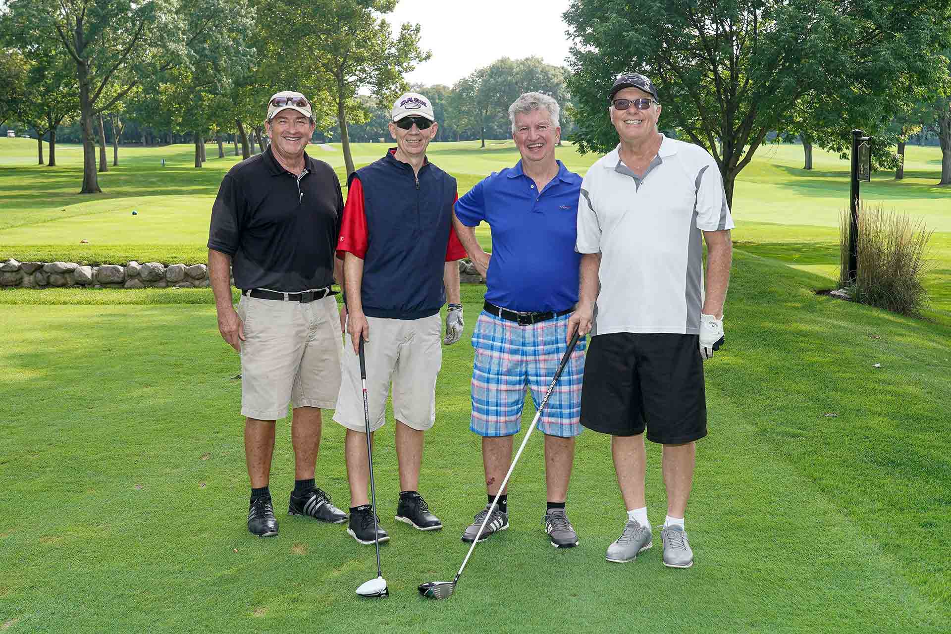 2019-endowment-classic-four-men-smiling-on-golf-course-with-clubs
