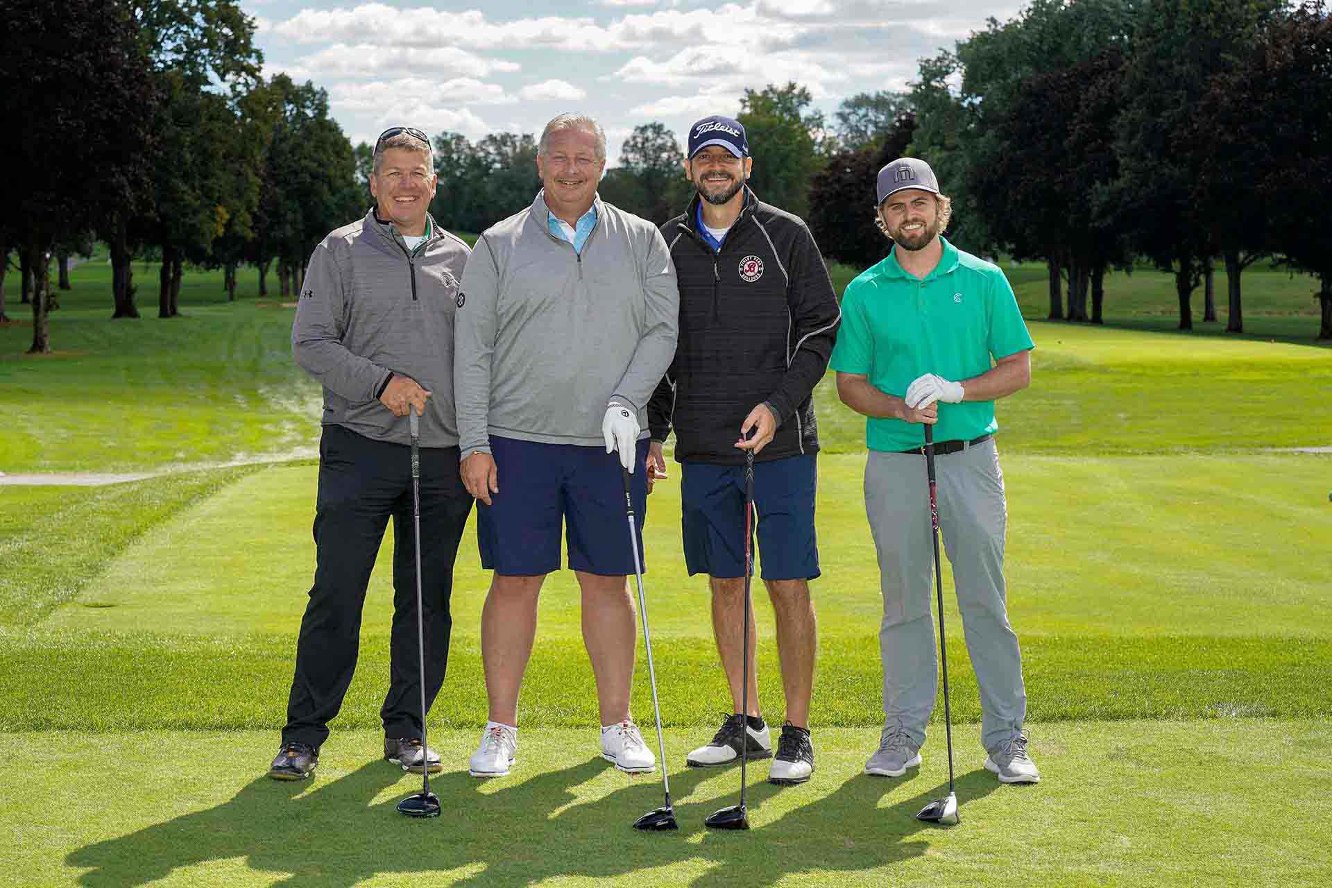 2020-endownment-classic-four-people-smile-for-photo-holding-golf-clubs