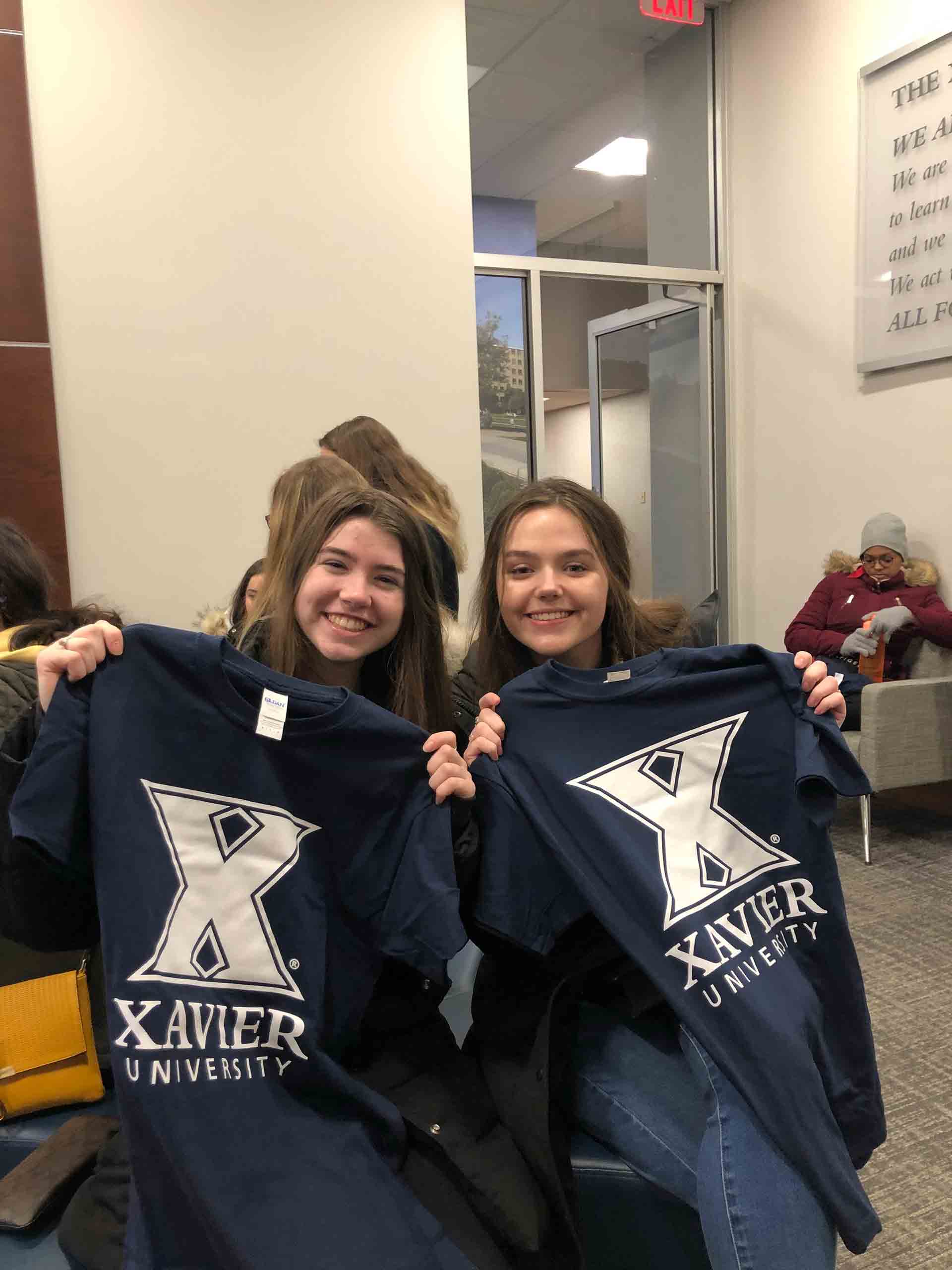 2020-explore-college-tour-students-holding-xavier-shirts