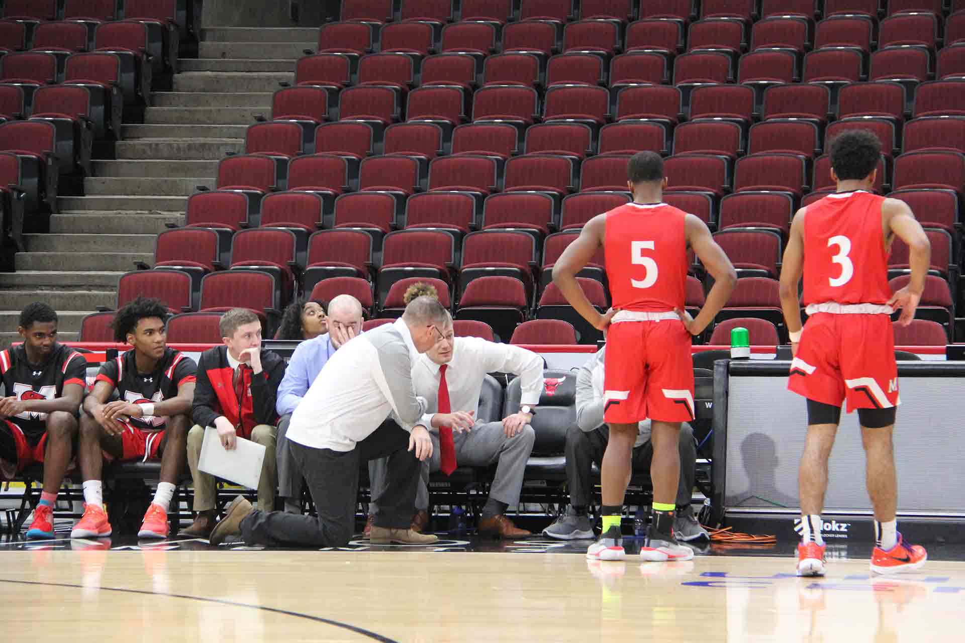 boys-basketball-vs-st-rita-coach-kneeling-next-to-other-coach