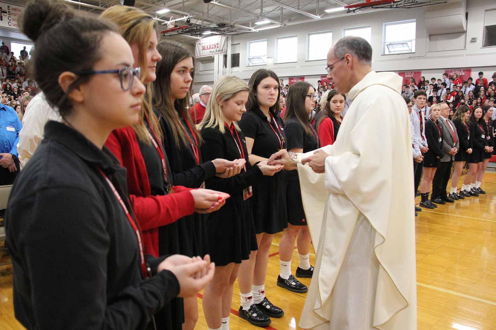 catholic-schools-week-mass-2020-priest-offering-bread-to-students