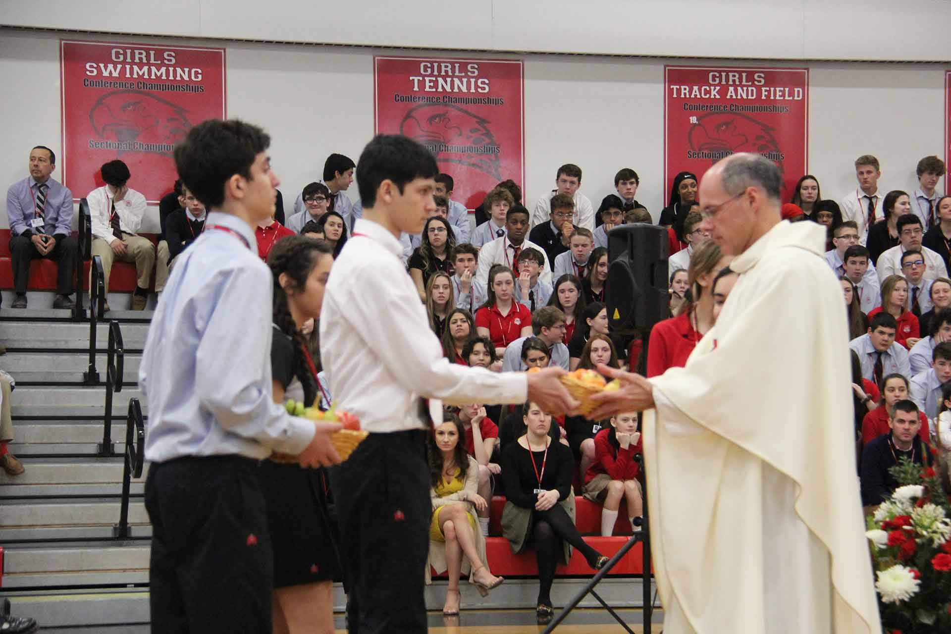 catholic-schools-week-mass-2020-two-students-handing-fruit-to-priest