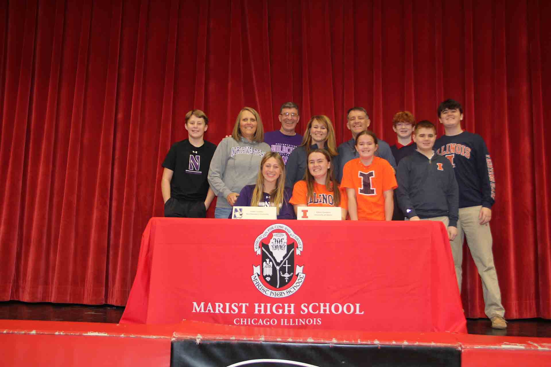two-students-sign-to-colleges-with-family-in-group-photo